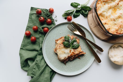 Gratin de pâtes au fromage servi dans une assiette verte, accompagné de tomates cerises et d'herbes fraîches.